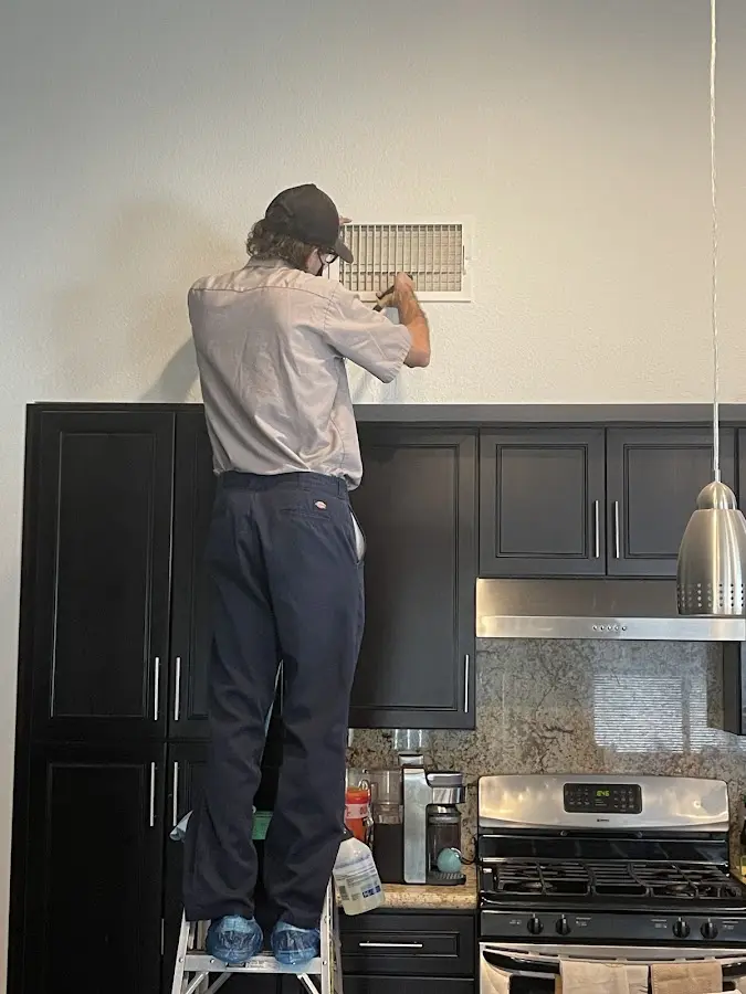 Technician inspecting an air vent during HVAC service in Indian Harbour Beach